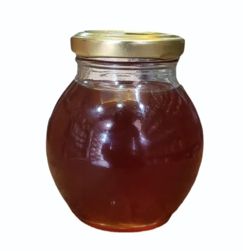 Jar of thick, golden wild forest honey with a wooden dipper.
